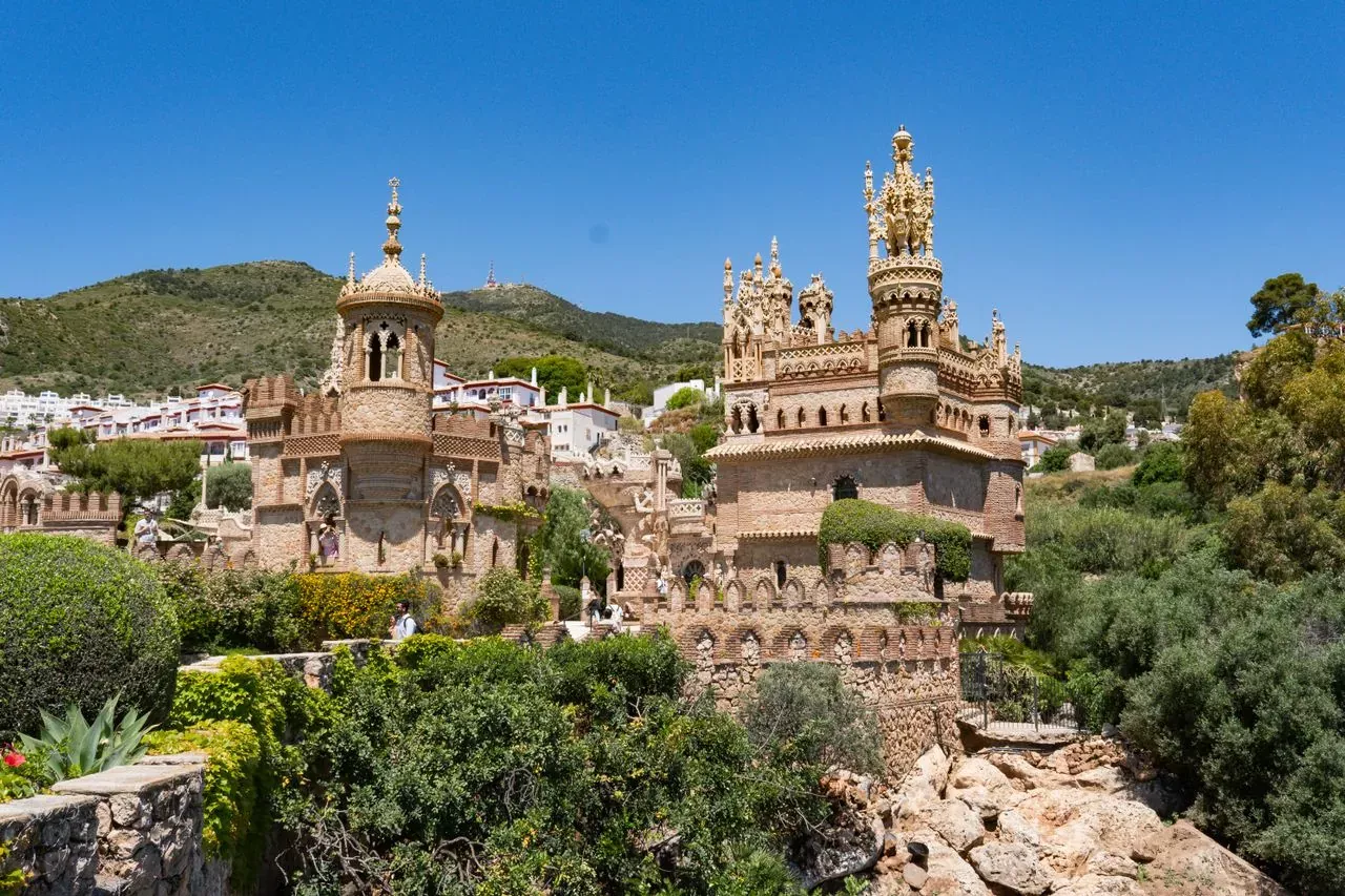 Ornate castle-like monument among trees in Benalmádena under a blue sky