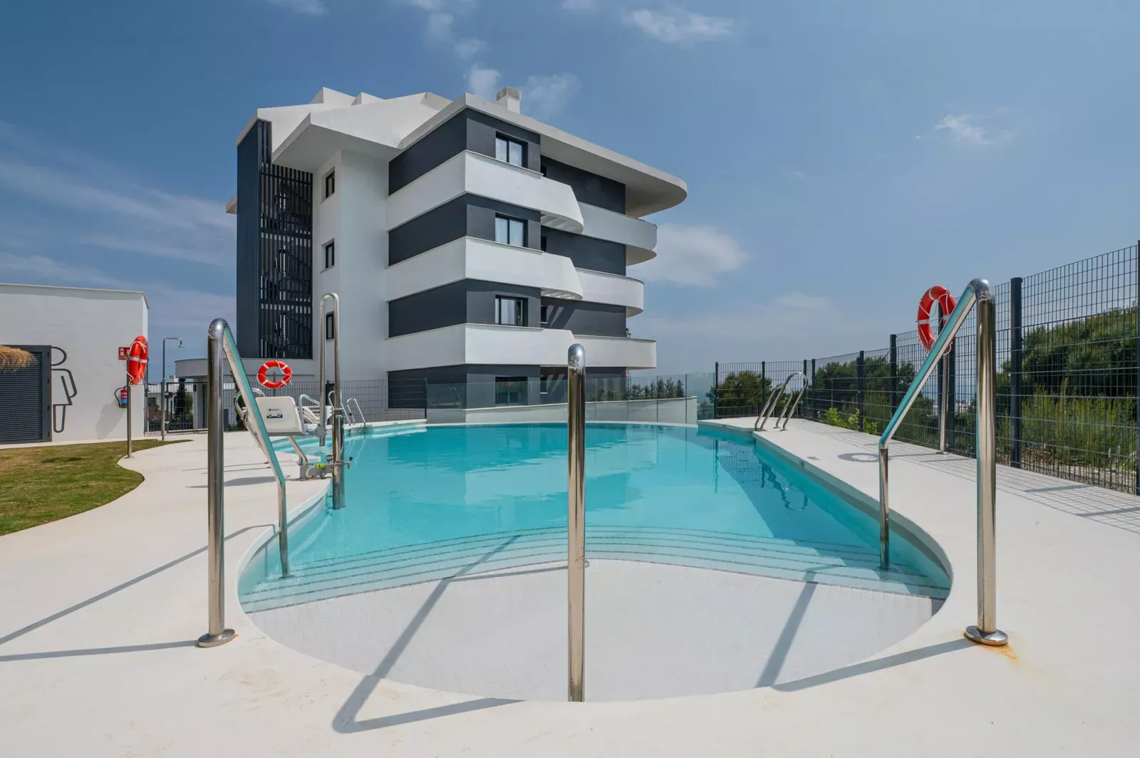 Communal pool with railing and a modern building at HW3