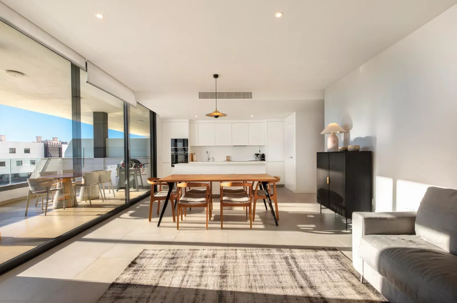 Open dining and living room with a large wooden table and floor-to-ceiling windows