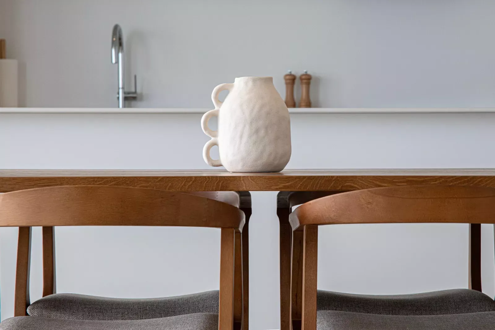 Wooden table detail with a white jug in the HW3 apartment