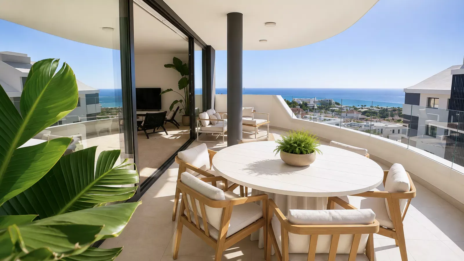 Terrace with a round dining table and plants facing the sea in Higuerón West
