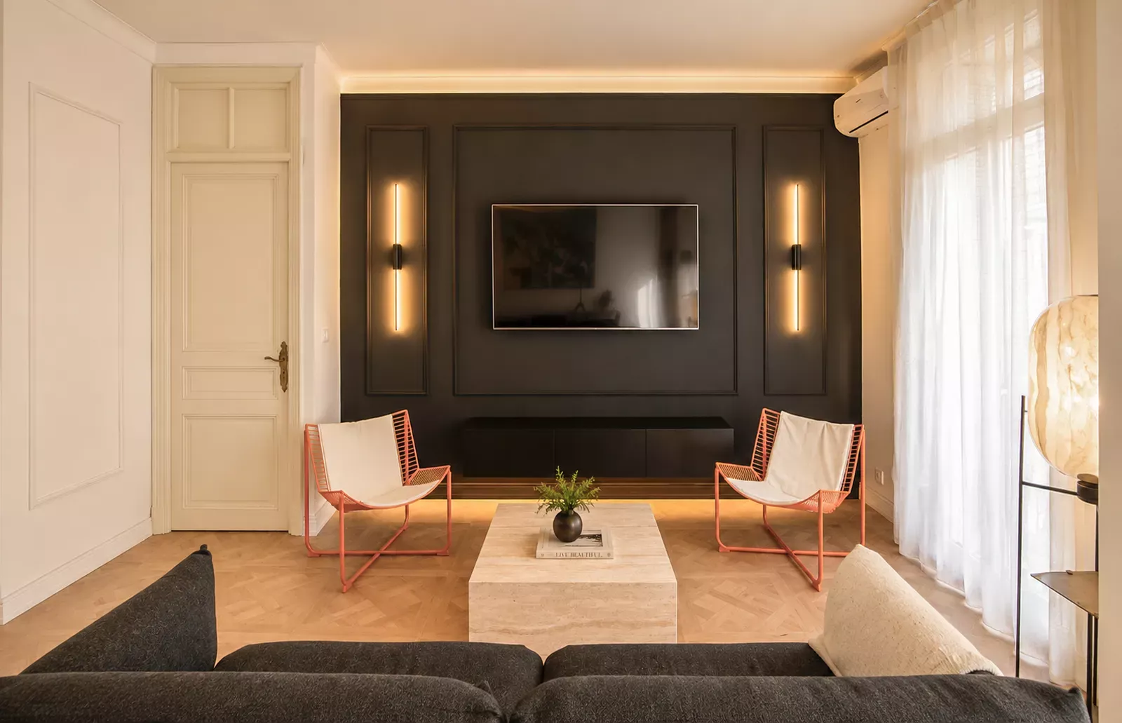 Living room with a dark sofa, armchairs and curtained window in Nice