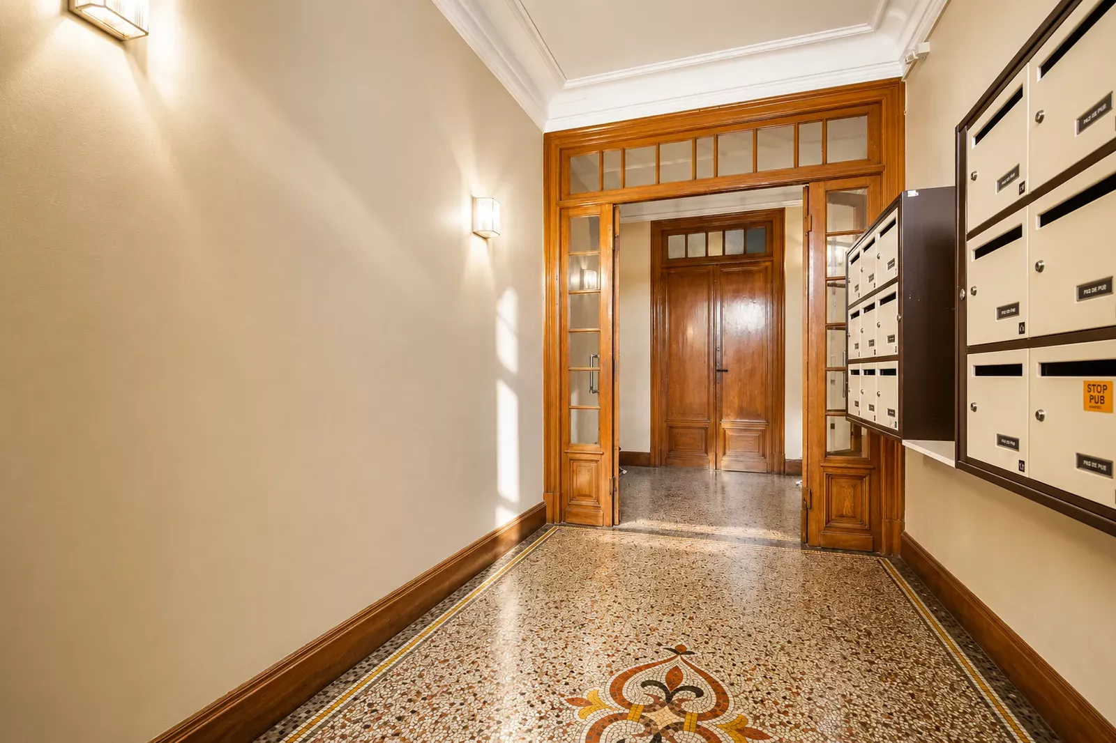 Building entrance hall with a wooden door, mosaic floor and mailboxes in Nice