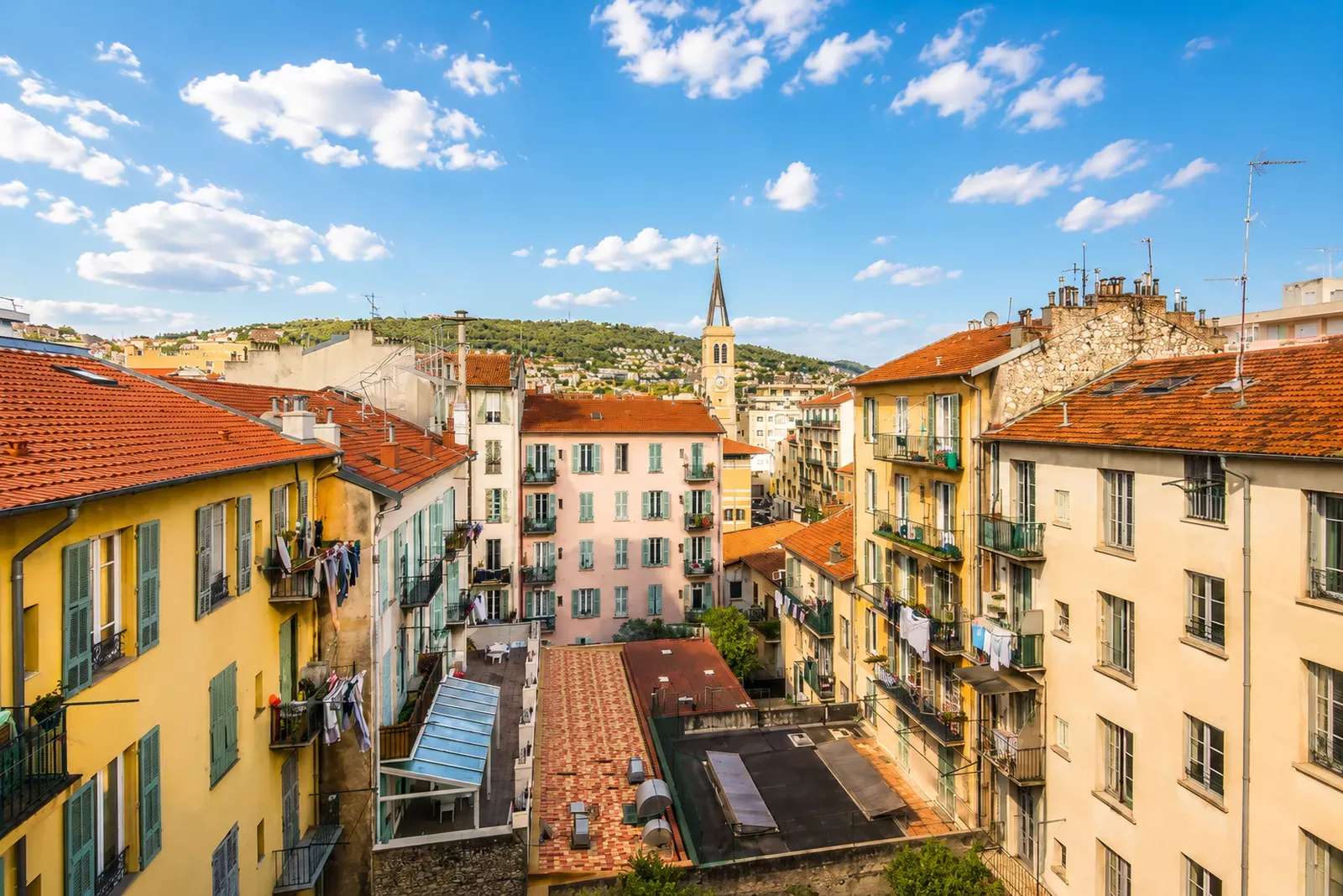 Yellow and orange apartment buildings along a street in Nice from a balcony
