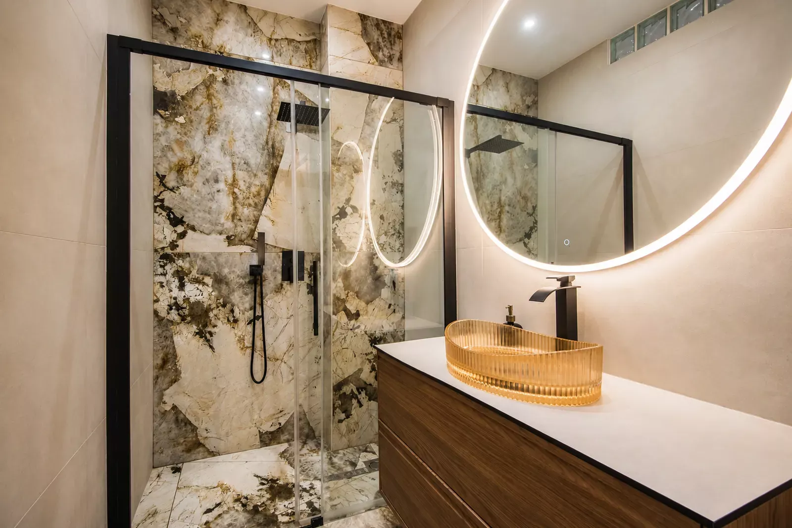Bathroom with a marble wall, round mirror and wooden vanity in the Nice apartment