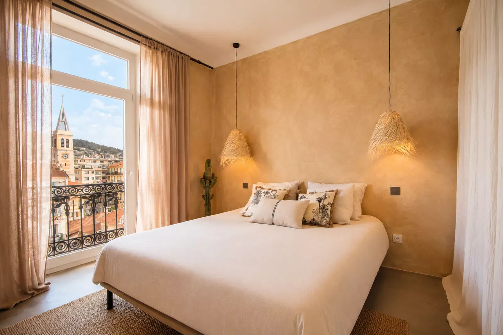 Warm-toned bedroom with a large window over the city in the Nice apartment