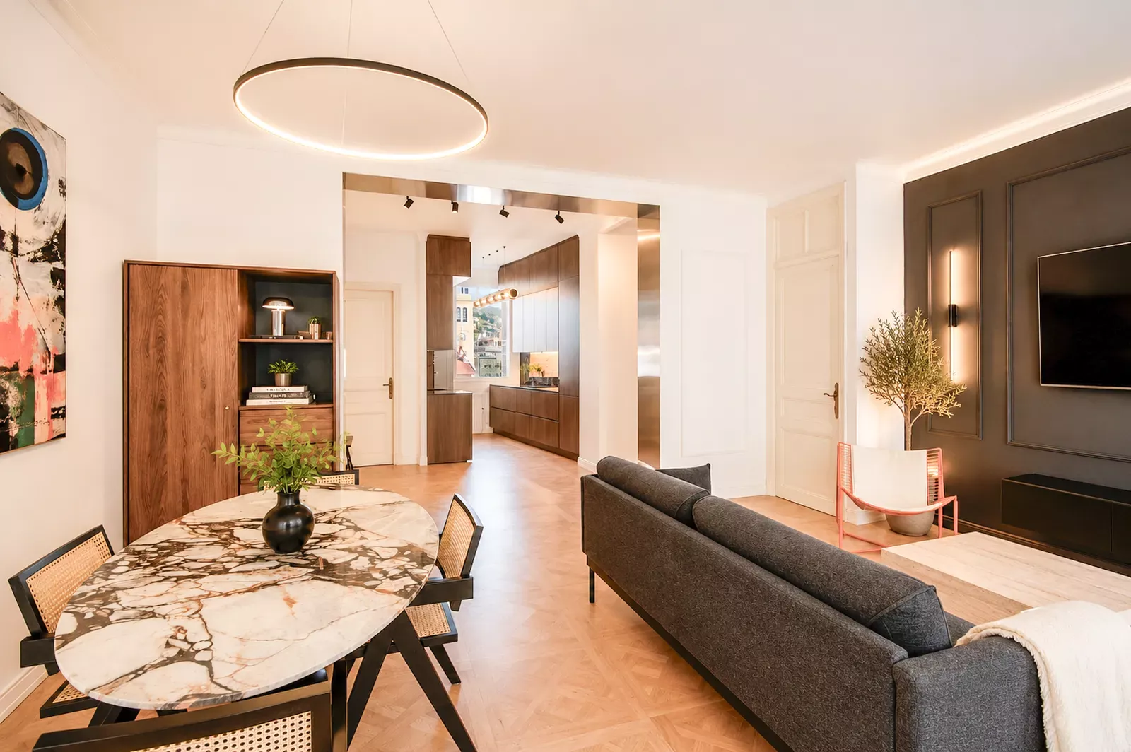 Living room with a dark sofa, round dining table and parquet in the Nice apartment