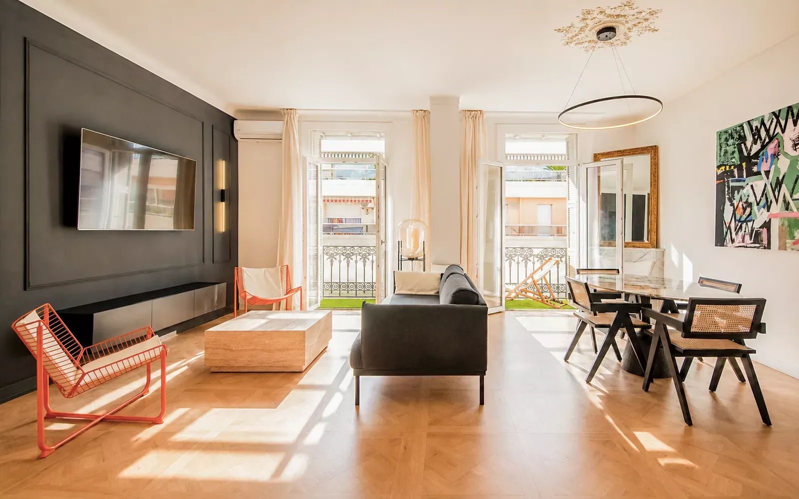 Living room with a dark TV wall, armchairs and balcony windows in Nice