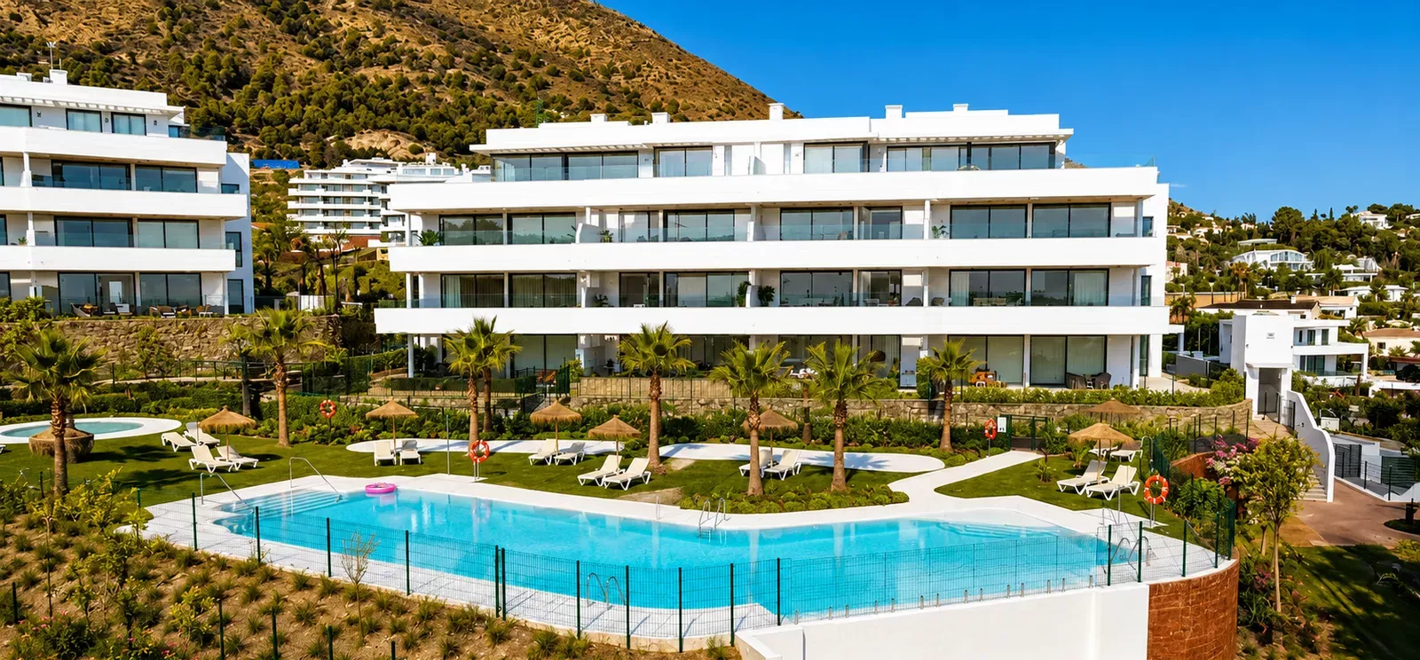 Modern white Higuerón West buildings overlooking a large turquoise pool