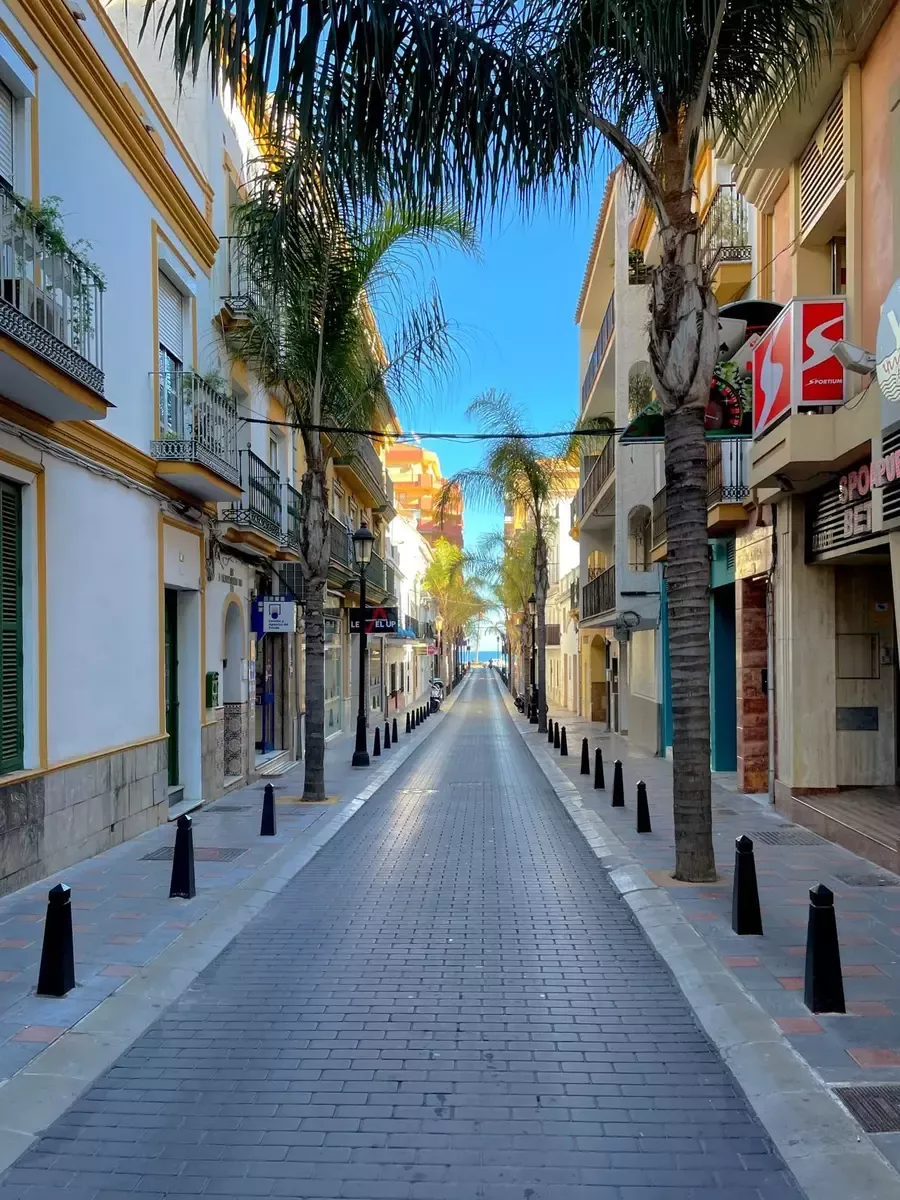 Narrow sunlit street lined with colourful façades in central Fuengirola
