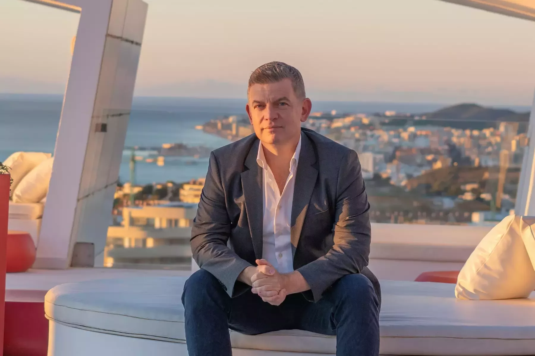 Jakob Skram-Jensen in a suit on a sunset terrace overlooking the sea